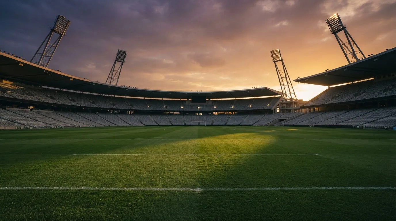 Un estadio de fútbol vacío con torres de iluminación al atardecer