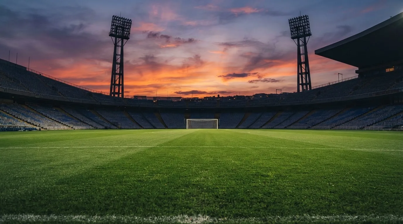 Un estadio de fútbol vacío con torres de iluminación al atardecer