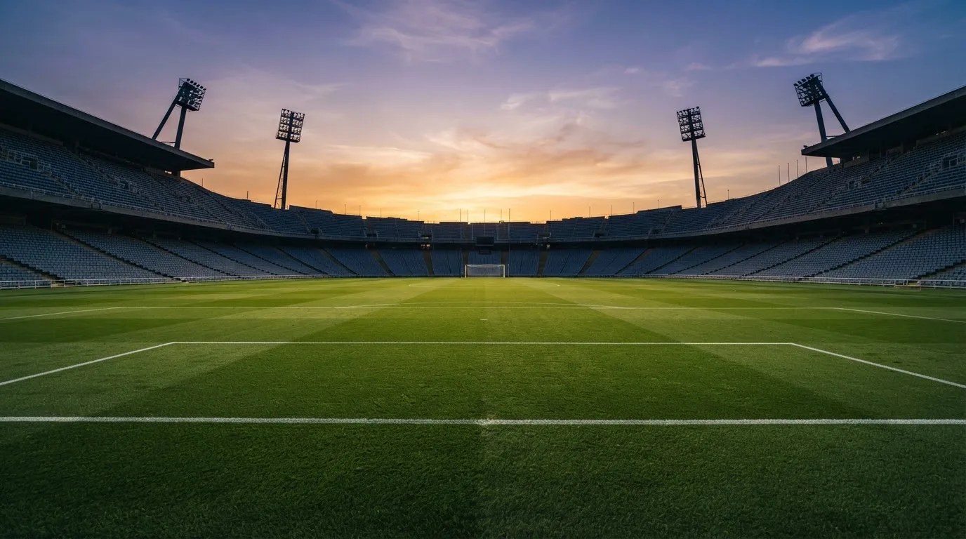 Un estadio de fútbol vacío con torres de iluminación al atardecer