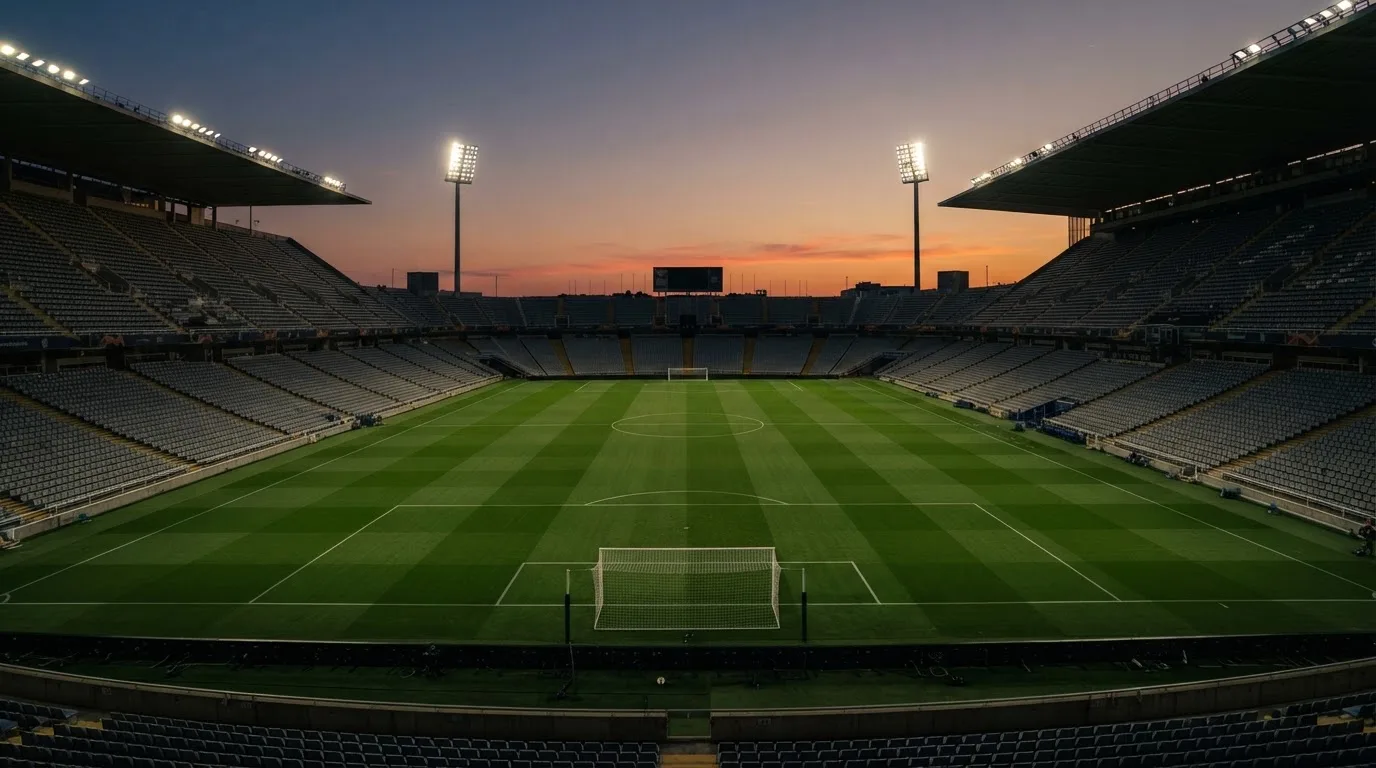 Un estadio de fútbol vacío con torres de iluminación al atardecer