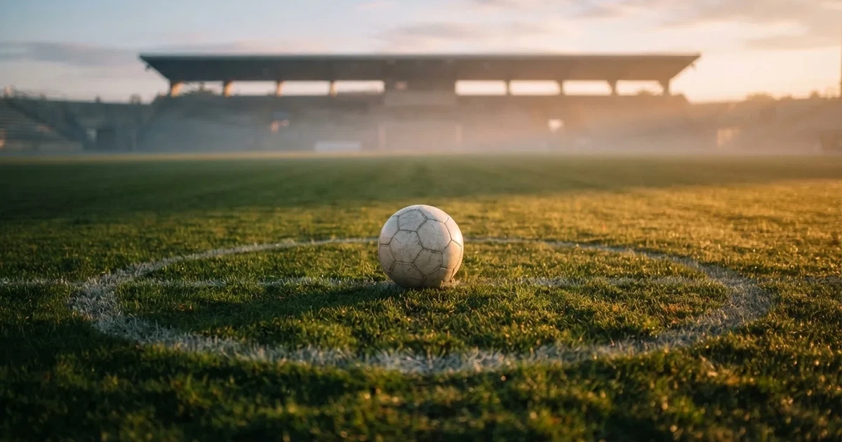 Un balón en el punto central de un campo de césped a la luz de la mañana