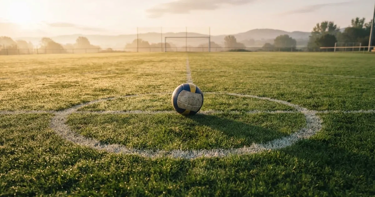 Un balón en el punto central de un campo de césped a la luz de la mañana