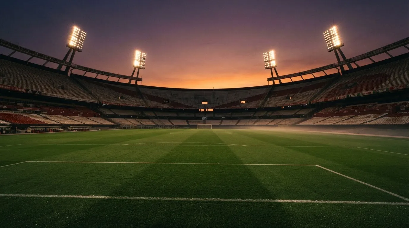 Un estadio de fútbol vacío con torres de iluminación al atardecer