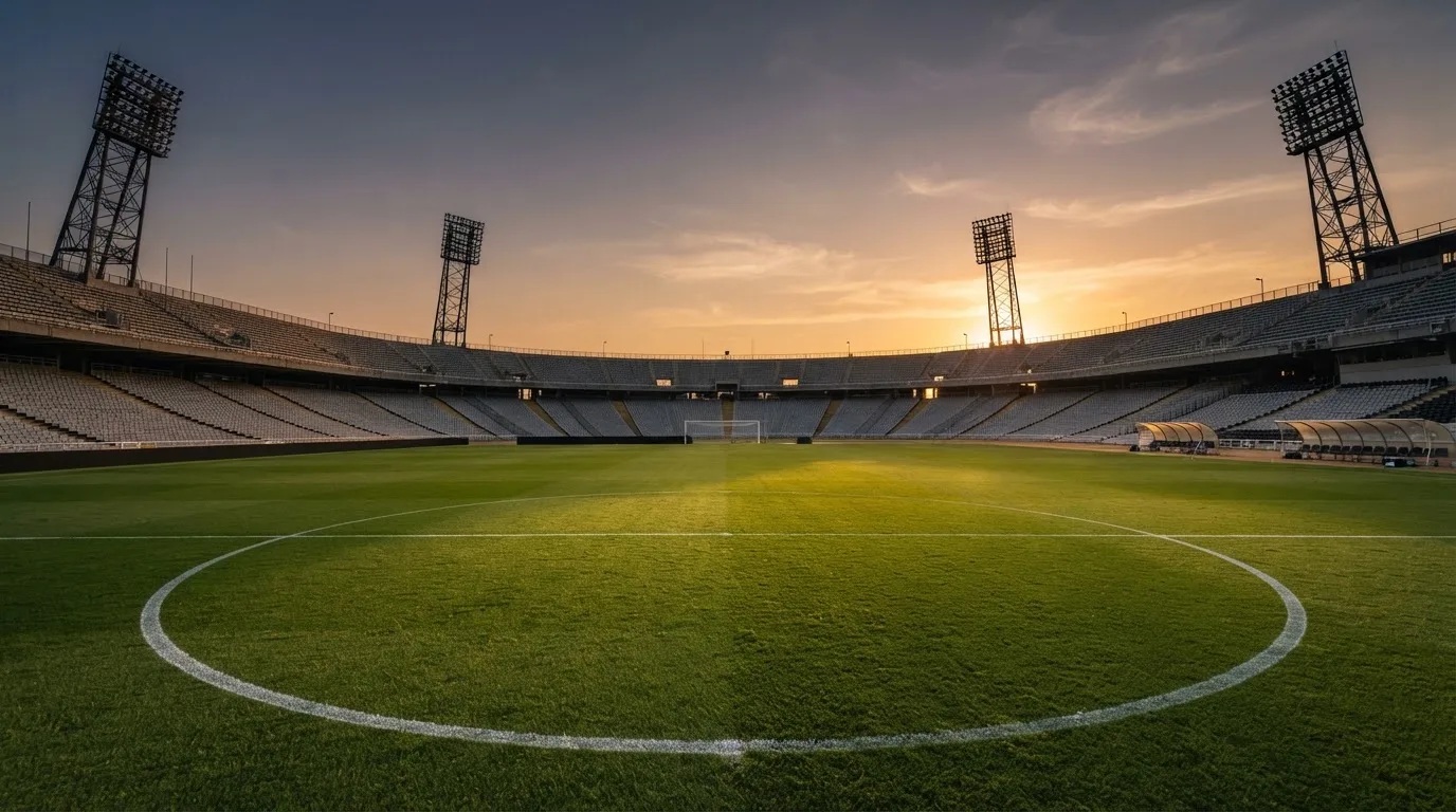 Un estadio de fútbol vacío con torres de iluminación al atardecer