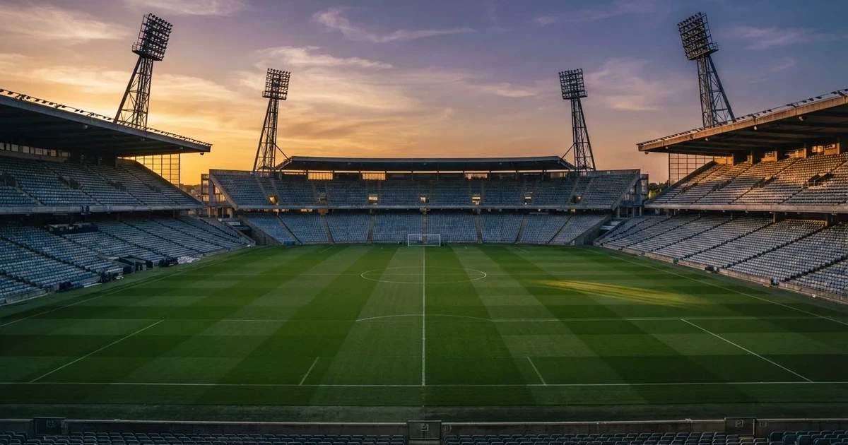 Un estadio de fútbol vacío con torres de iluminación al atardecer