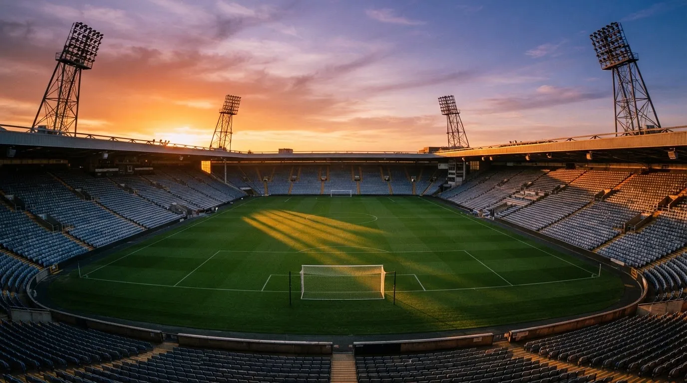 Un estadio de fútbol vacío con torres de iluminación al atardecer