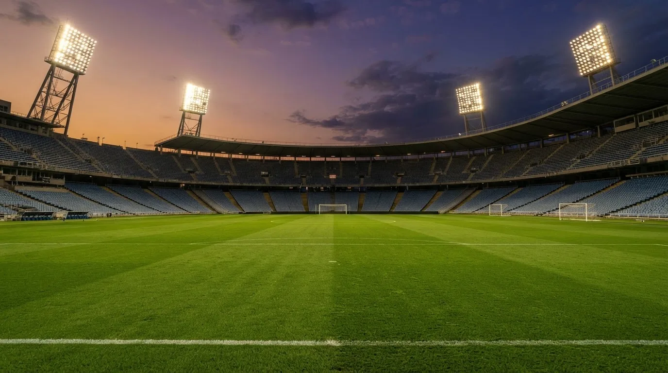 Un estadio de fútbol vacío con torres de iluminación al atardecer