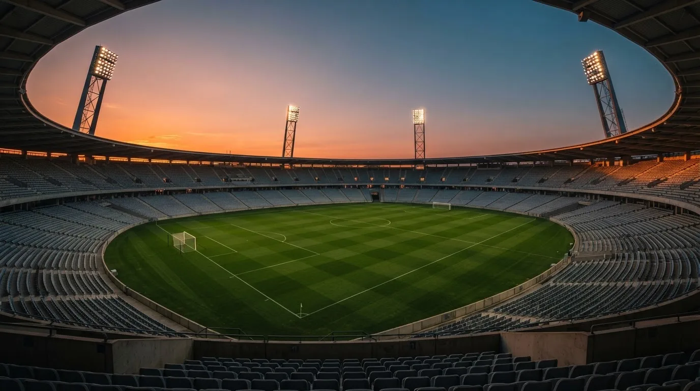 Un estadio de fútbol vacío con torres de iluminación al atardecer