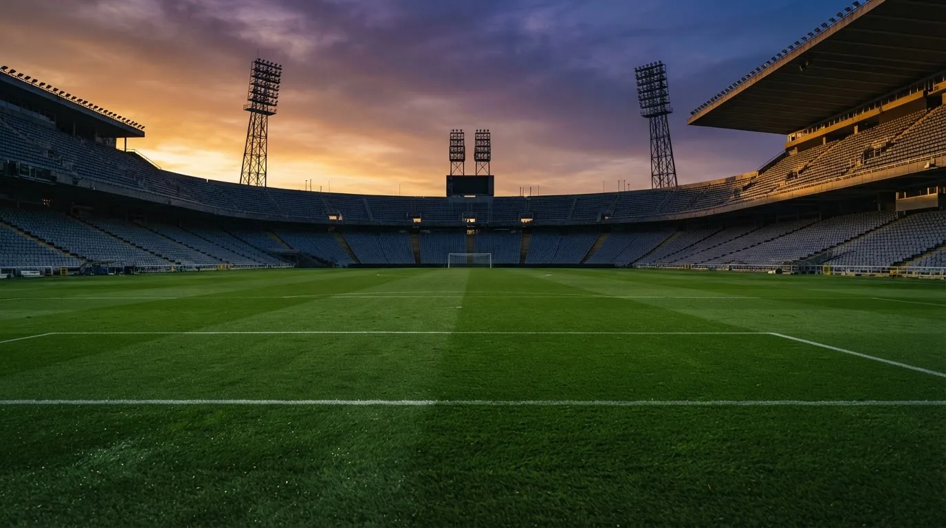 Un estadio de fútbol vacío con torres de iluminación al atardecer