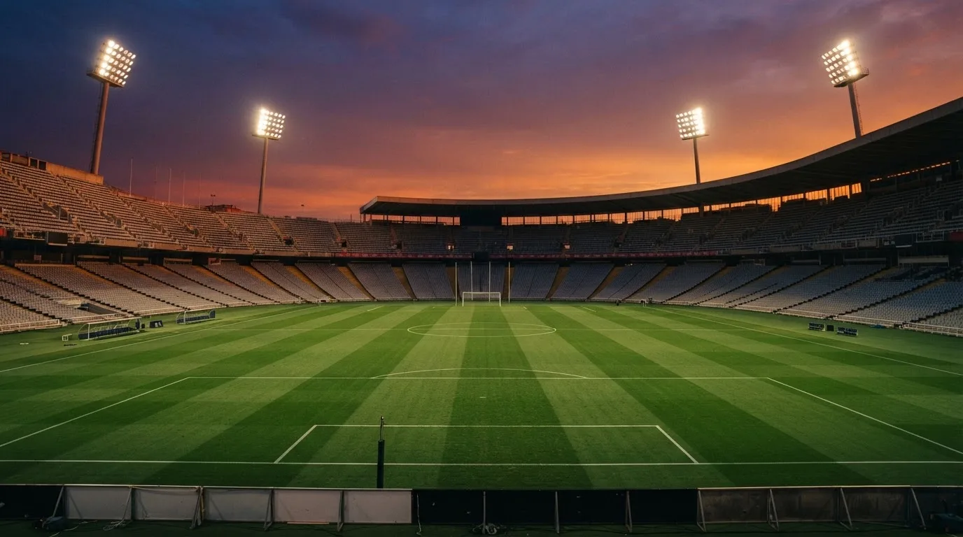 Un estadio de fútbol vacío con torres de iluminación al atardecer