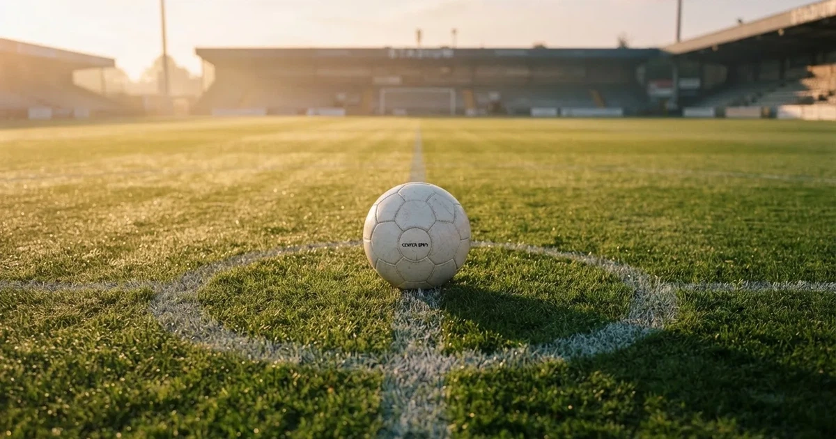 Un balón en el punto central de un campo de césped a la luz de la mañana