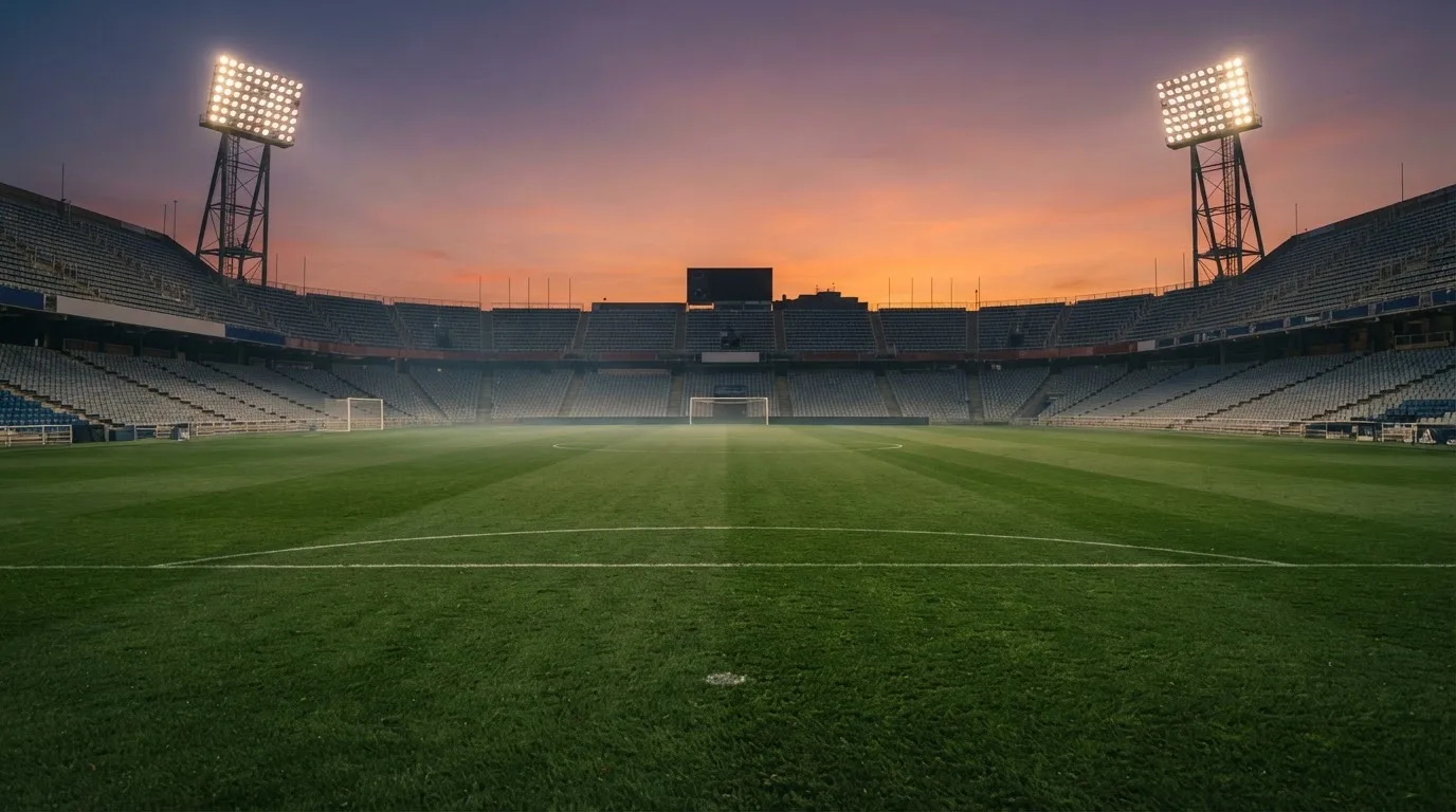 Un estadio de fútbol vacío con torres de iluminación al atardecer