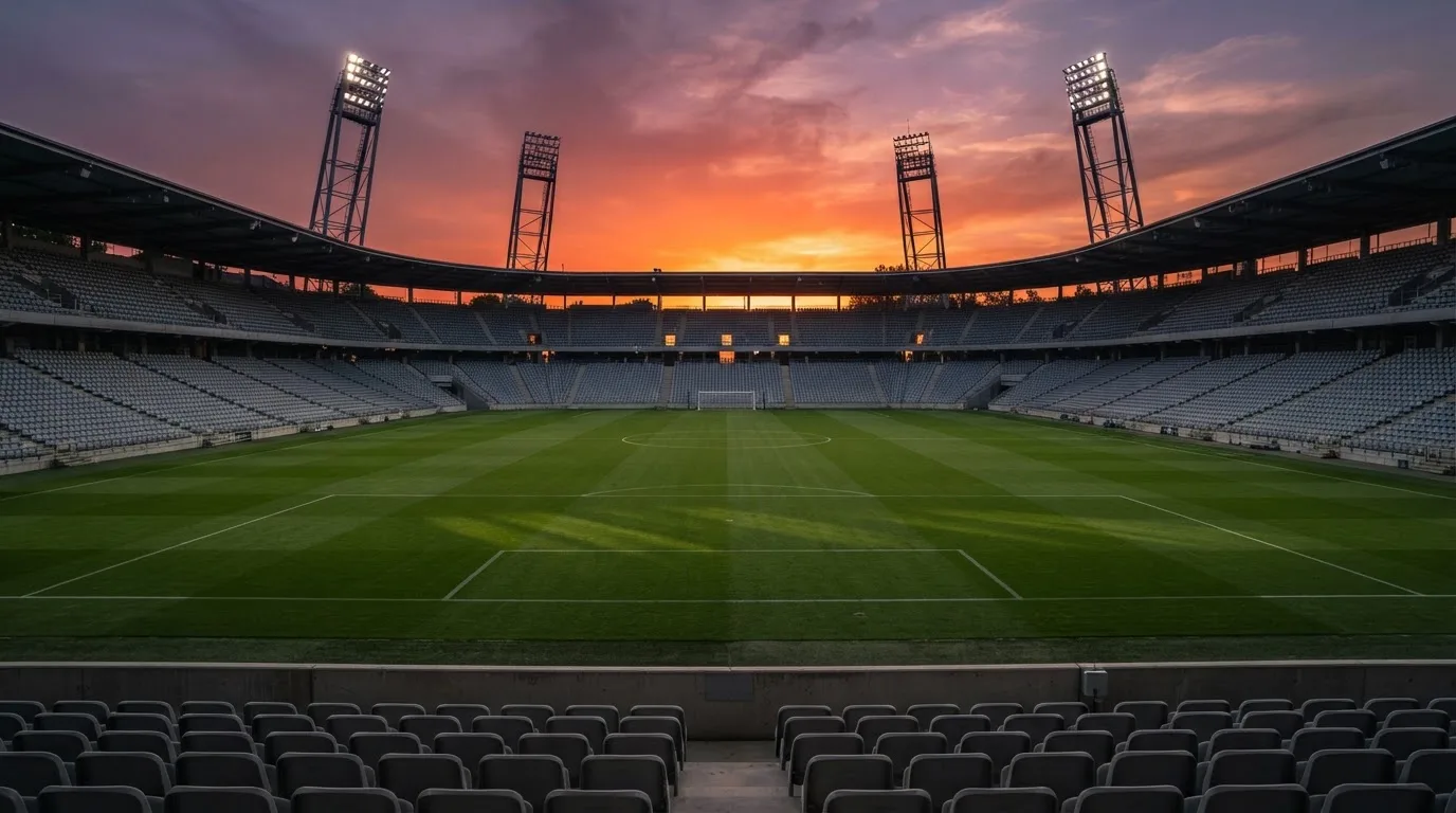 Un estadio de fútbol vacío con torres de iluminación al atardecer