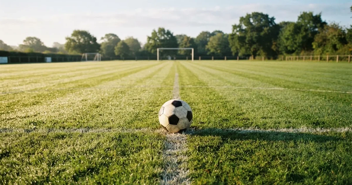 Un balón en el punto central de un campo de césped a la luz de la mañana