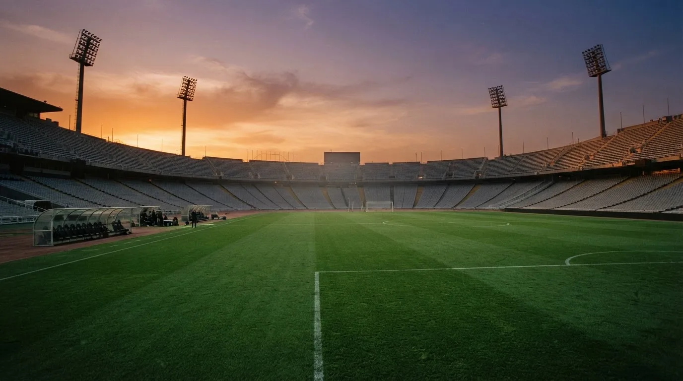 Un estadio de fútbol vacío con torres de iluminación al atardecer