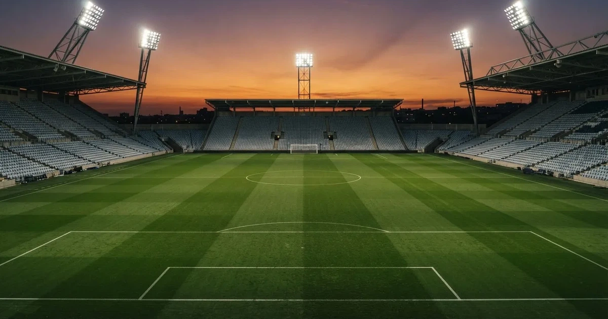 Un estadio de fútbol vacío con torres de iluminación al atardecer