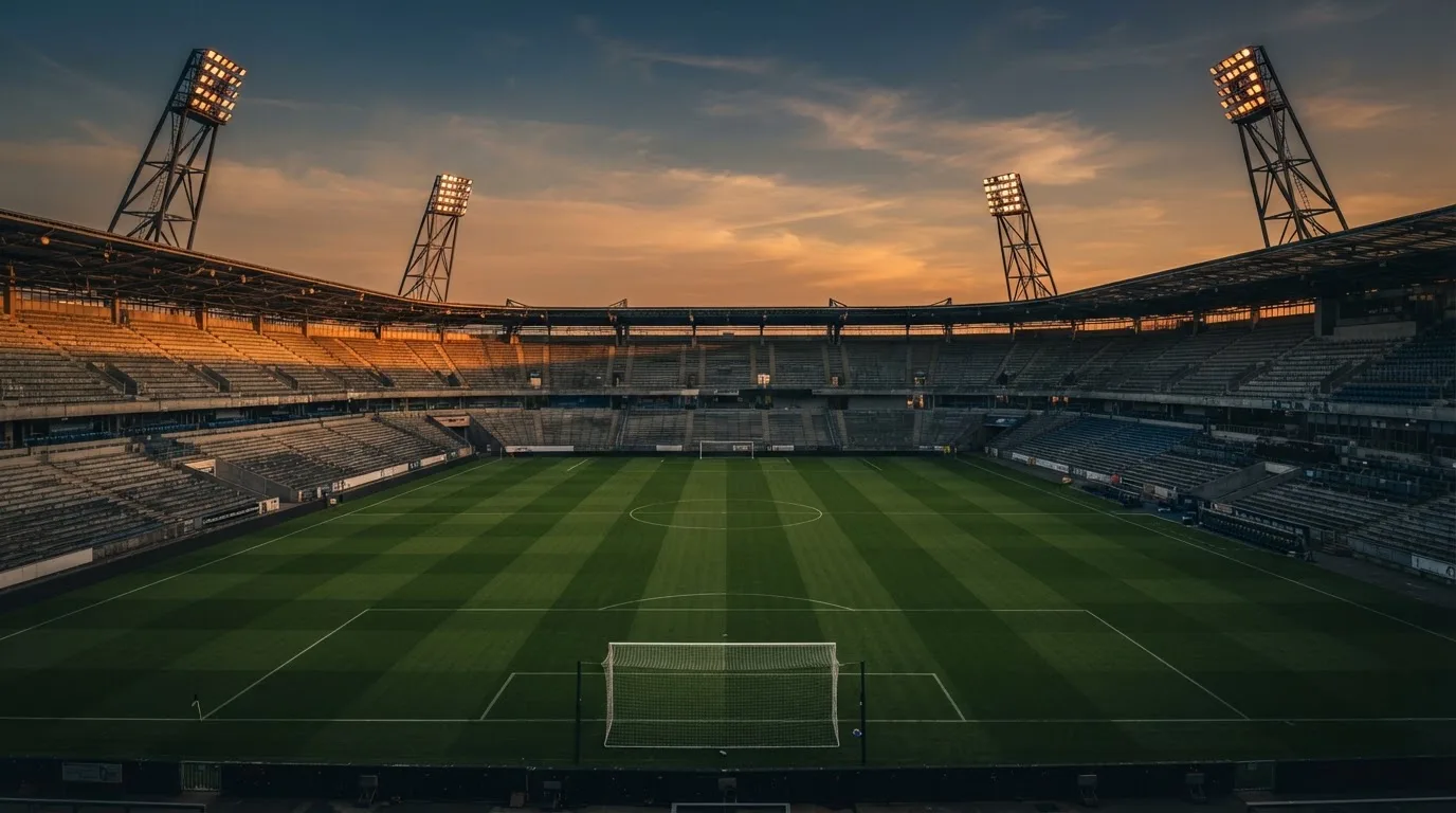 Un estadio de fútbol vacío con torres de iluminación al atardecer